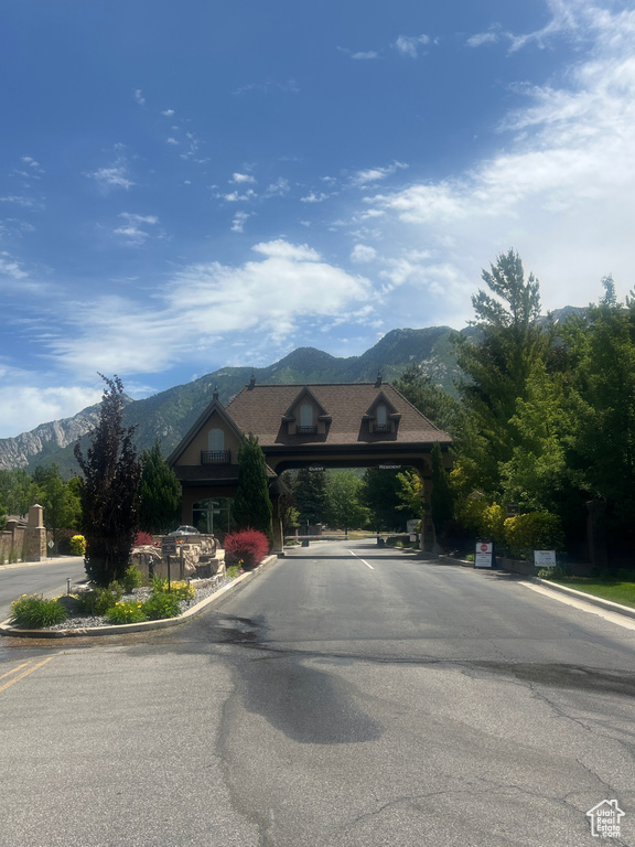 View of asphalt road with a mountain view, curbs, and a gated entry
