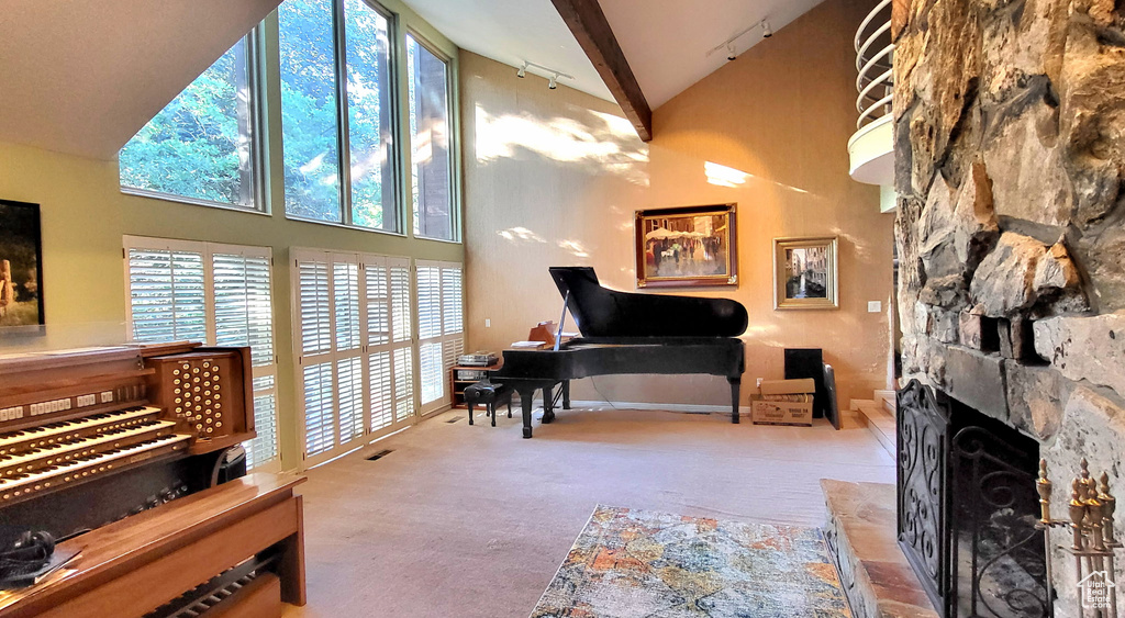 Sitting room with high vaulted ceiling, carpet floors, track lighting, plenty of natural light, and a desk