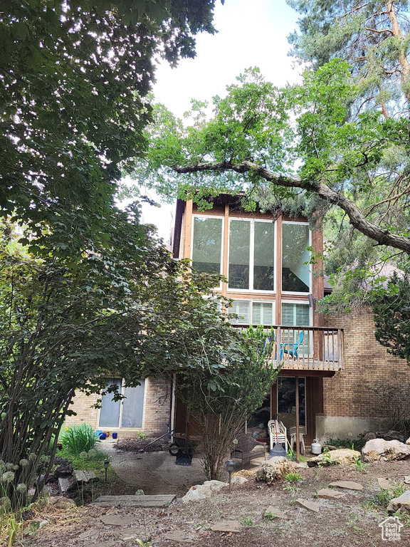 Back of property featuring a wooden deck and brick siding
