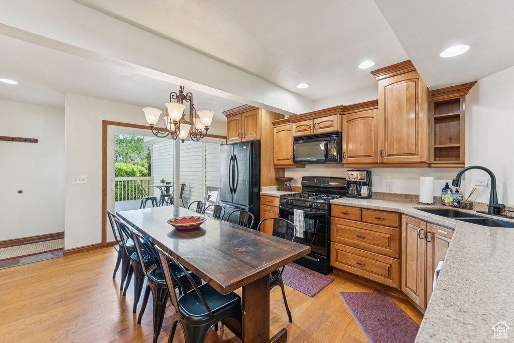 Kitchen with black appliances, light wood-style flooring, light countertops, a chandelier, and decorative light fixtures