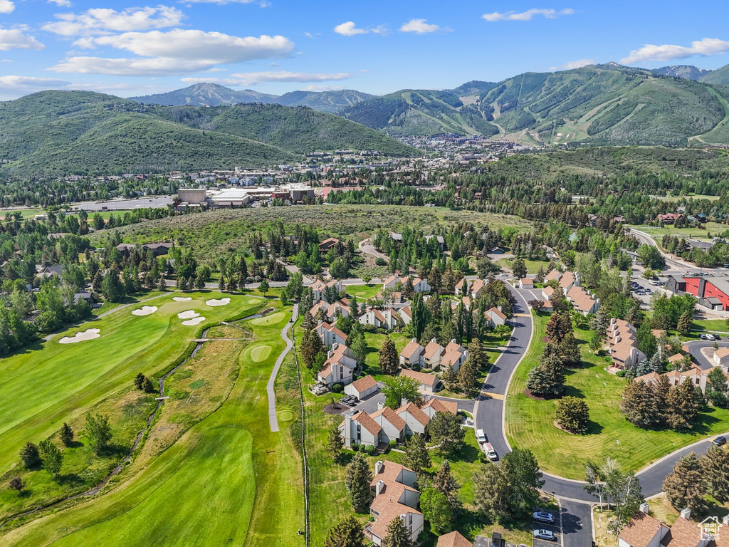 Aerial view of property and surrounding area featuring a mountainous background and nearby suburban area