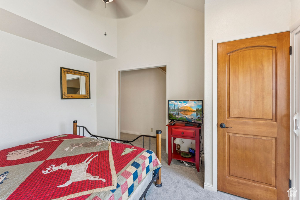 Bedroom with light colored carpet, a towering ceiling, a ceiling fan, and a closet