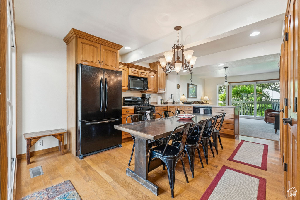 Kitchen featuring black appliances, a peninsula, light wood-type flooring, a chandelier, and recessed lighting