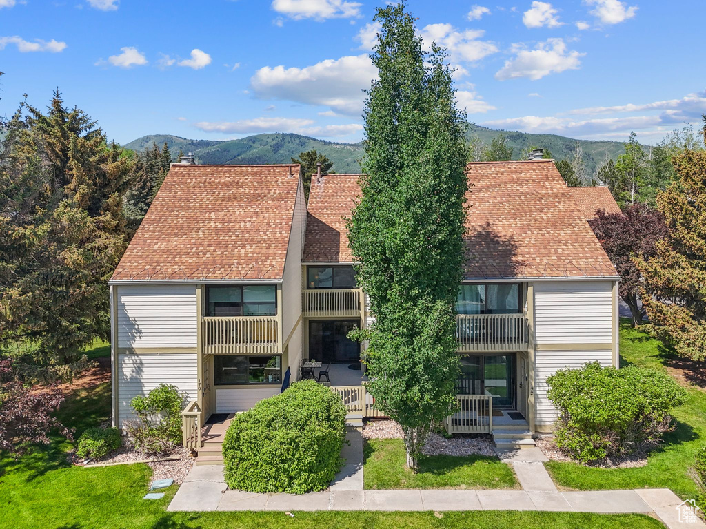 View of front of house featuring a balcony, a mountain view, a front lawn, and a chimney