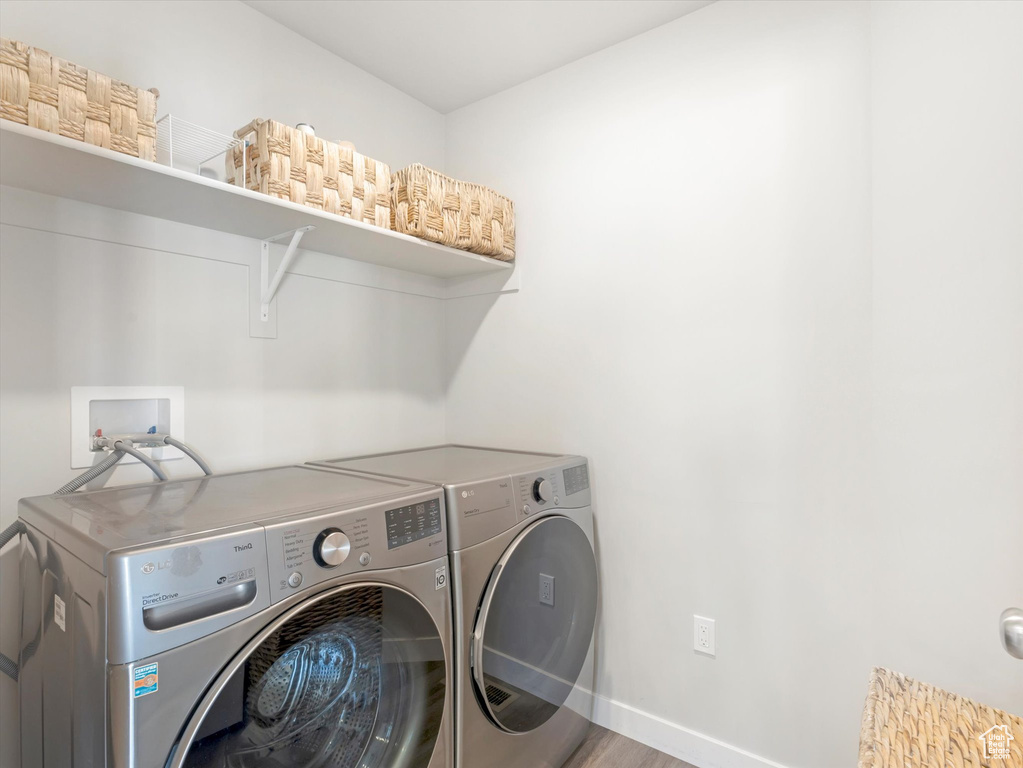 Washroom with independent washer and dryer, baseboards, and wood finished floors