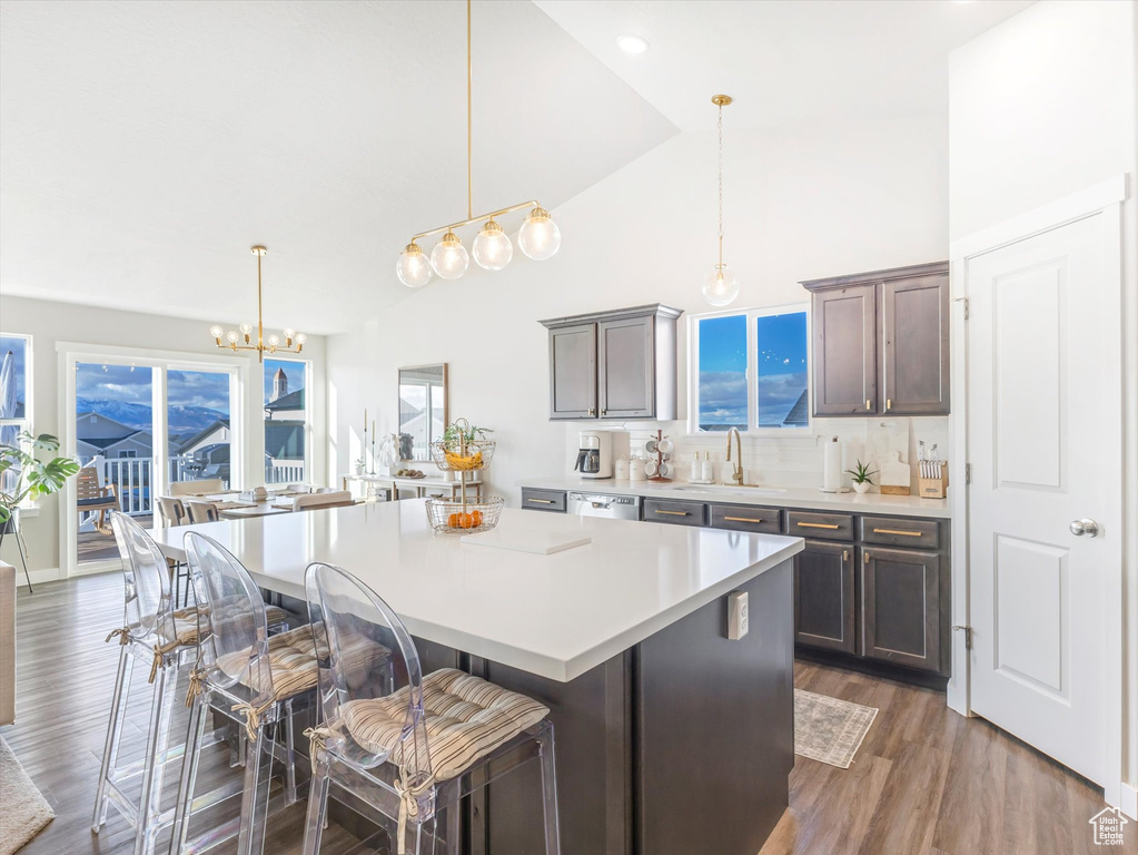Kitchen featuring a sink, a chandelier, a center island, light countertops, and a breakfast bar area