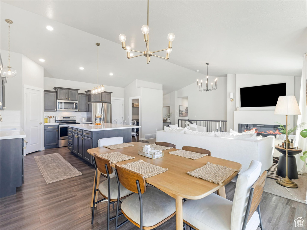 Dining space with a chandelier, lofted ceiling, dark wood finished floors, and recessed lighting