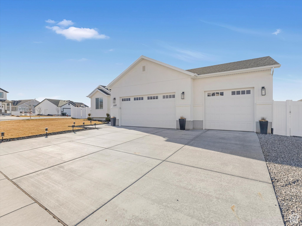 View of front of home with an attached garage, driveway, and stucco siding