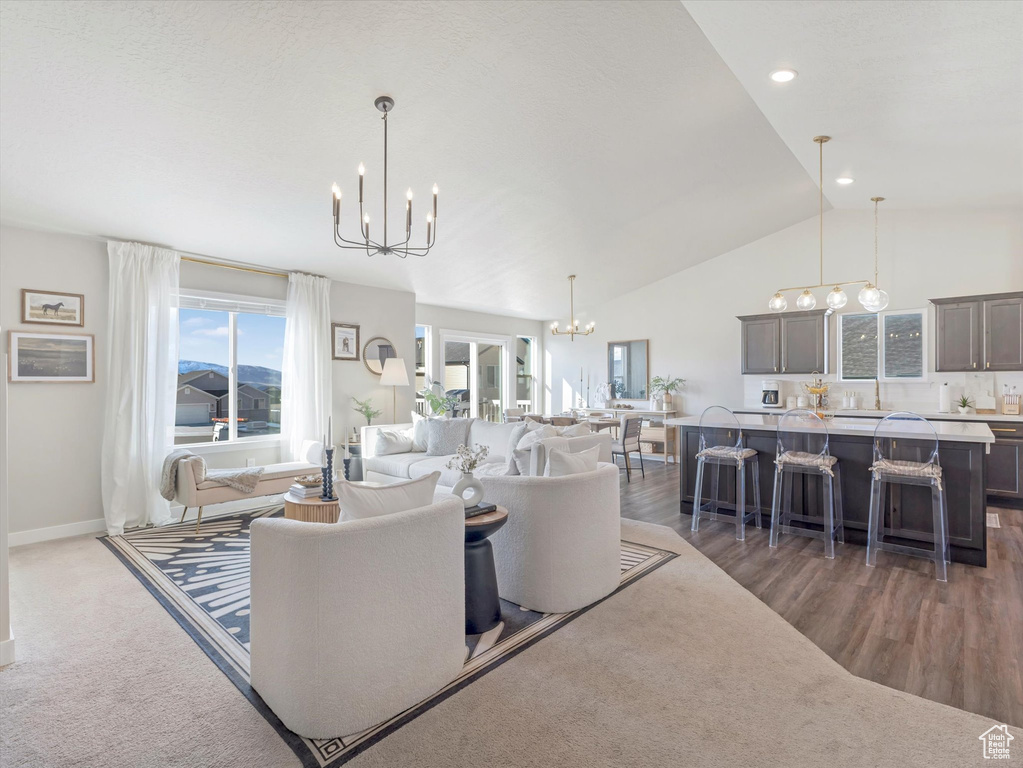 Living room with a chandelier, vaulted ceiling, wood finished floors, baseboards, and recessed lighting