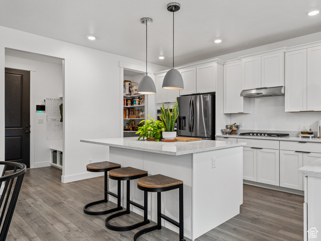 Kitchen with stainless steel appliances, a kitchen island, dark wood-type flooring, white cabinetry, and recessed lighting
