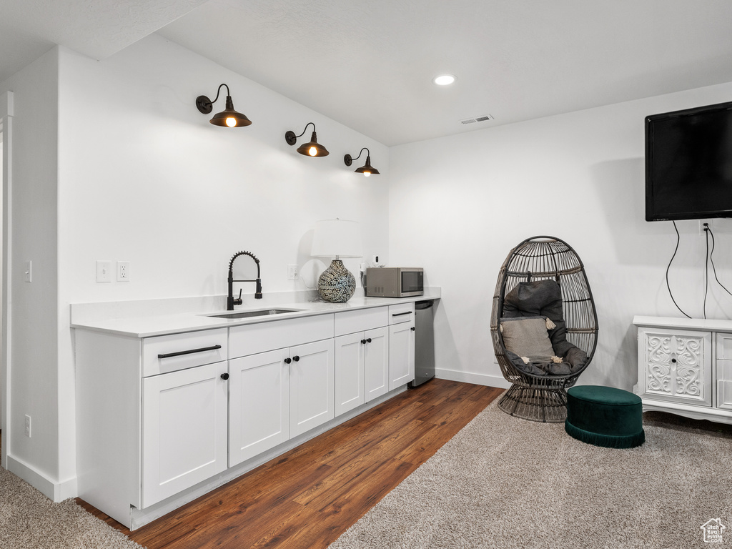 Bar with stainless steel microwave, dark wood-type flooring, and recessed lighting