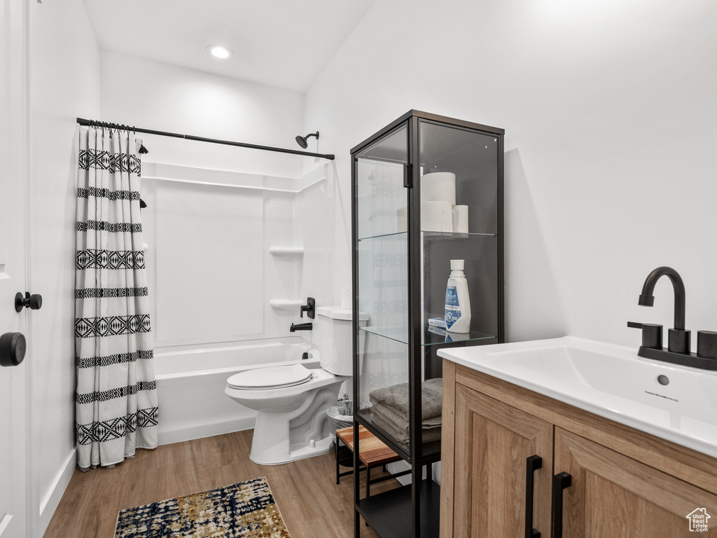 Full bathroom featuring shower / bath combination with curtain, wood finished floors, and vanity