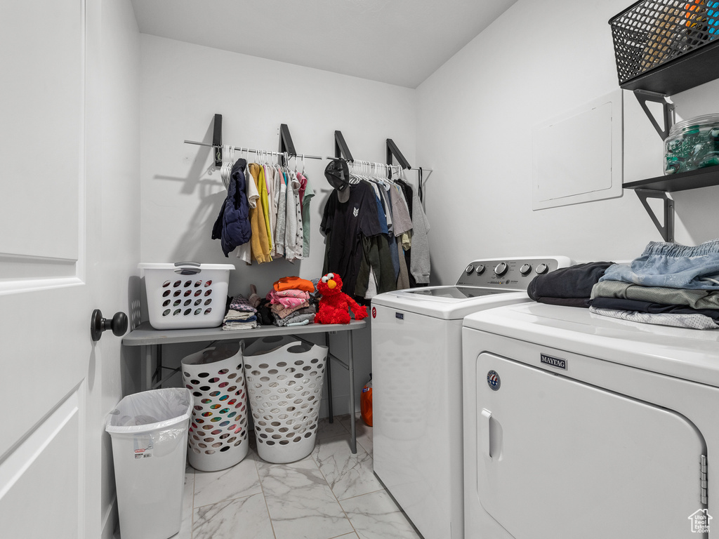 Washroom featuring washer and dryer and light marble finish flooring