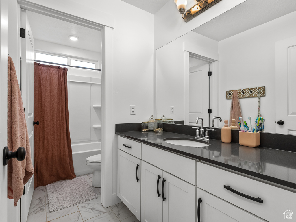 Full bath featuring vanity, shower / bath combo, and marble finish flooring