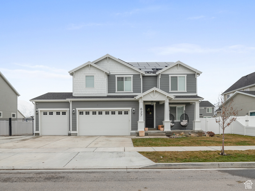 Craftsman house featuring solar panels, covered porch, concrete driveway, and an attached garage