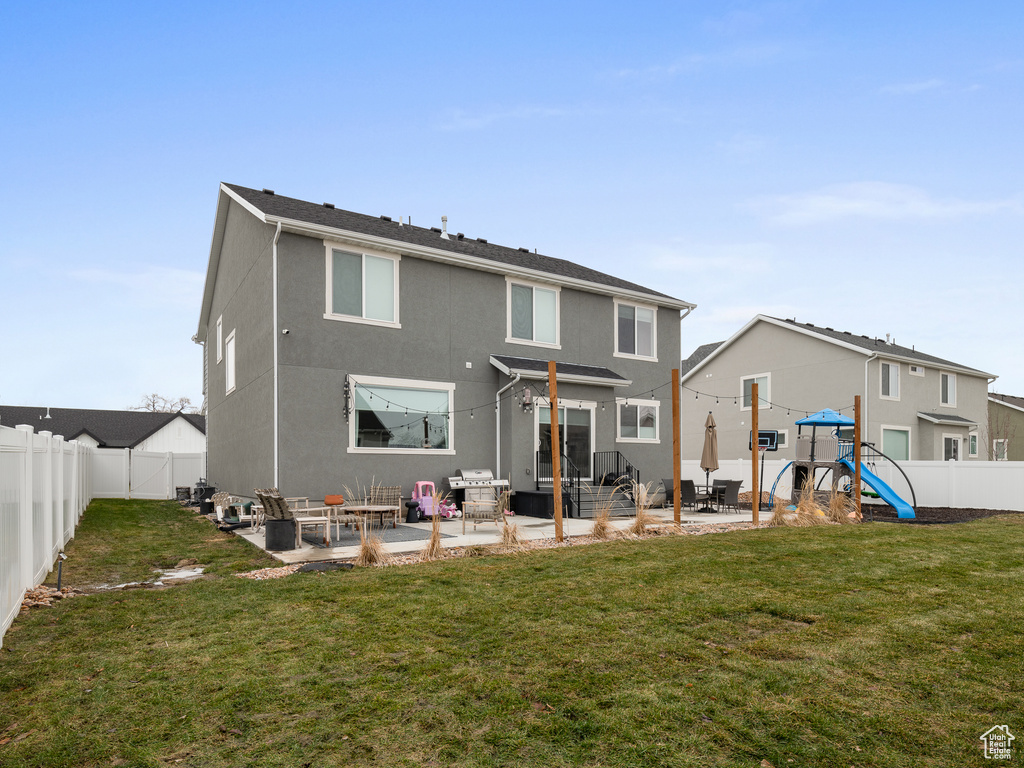 Rear view of house with a patio area, a fenced backyard, a playground, and stucco siding