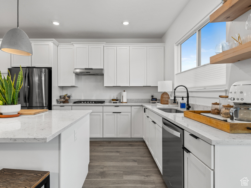 Kitchen featuring appliances with stainless steel finishes, under cabinet range hood, white cabinetry, recessed lighting, and decorative light fixtures