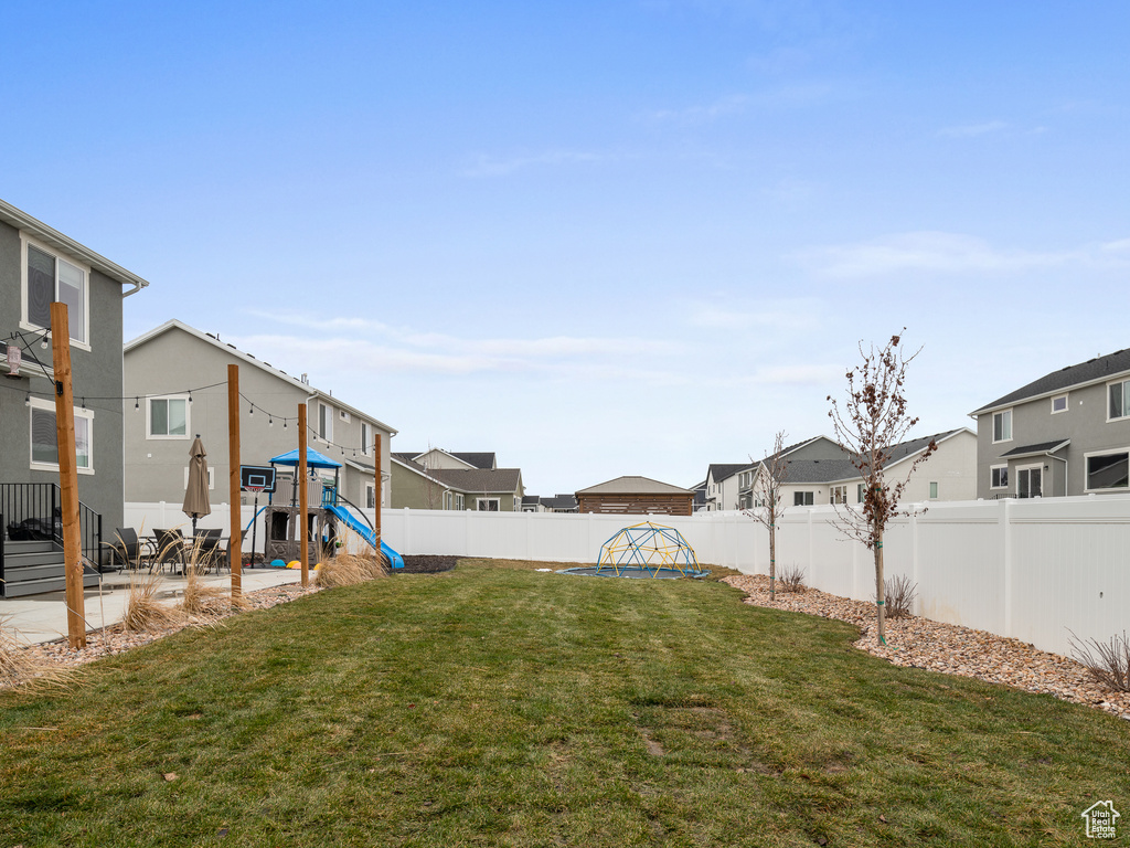 Fenced backyard with a playground, a residential view, and a patio