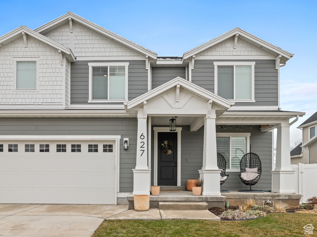 Craftsman-style home featuring covered porch, a garage, and driveway