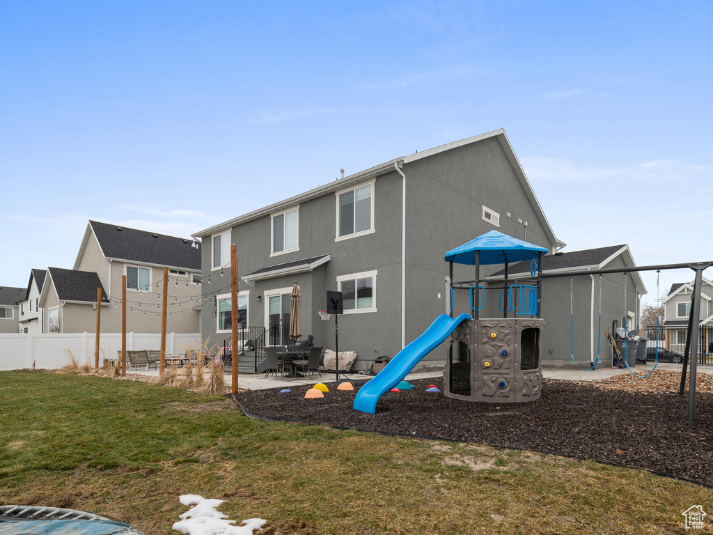 Rear view of property featuring a playground, a residential view, and stucco siding