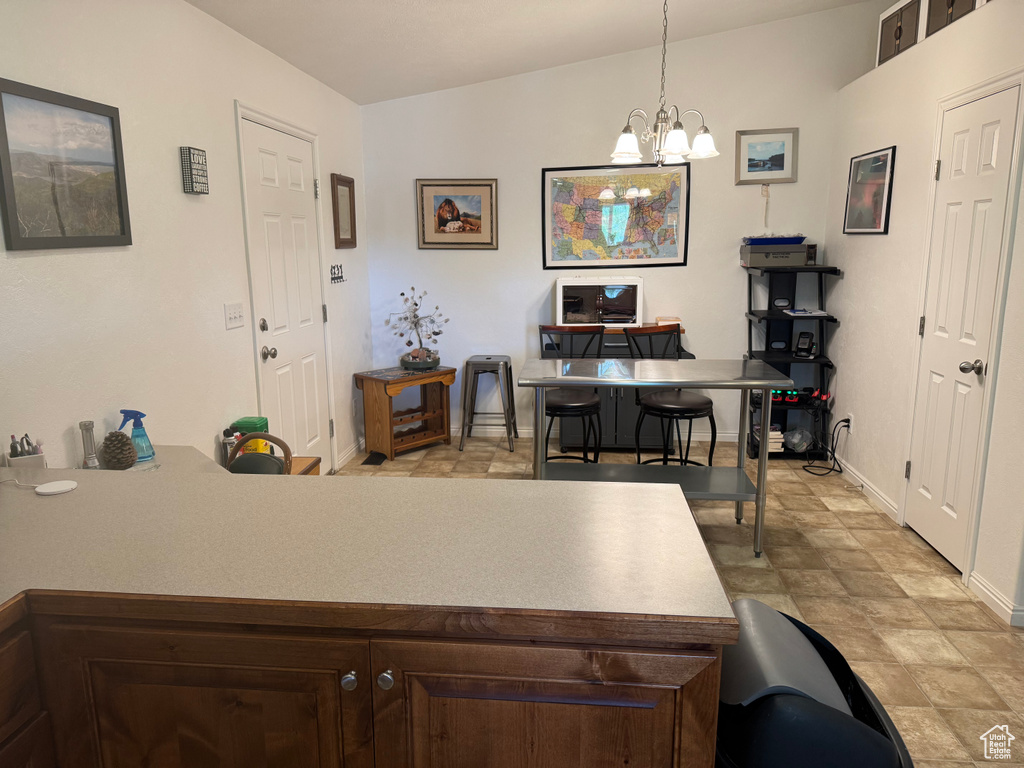 Kitchen with dark brown cabinets, a desk, a chandelier, decorative light fixtures, and light countertops