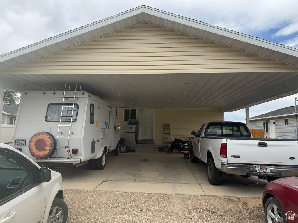 View of vehicle parking featuring an attached carport and dirt driveway