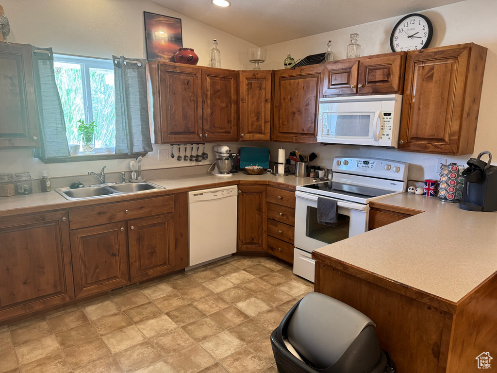 Kitchen featuring white appliances, light countertops, a peninsula, brown cabinetry, and recessed lighting