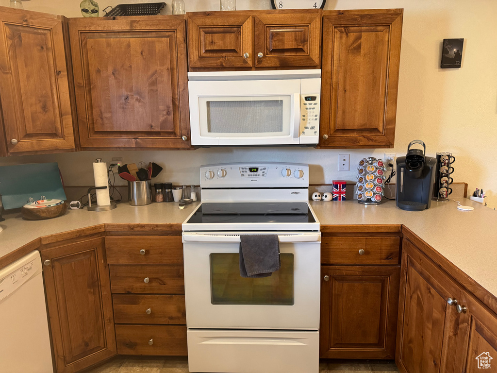 Kitchen featuring white appliances, light countertops, and brown cabinetry