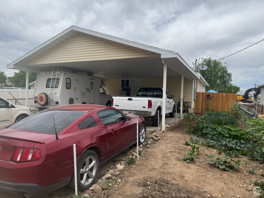 View of property exterior featuring a carport and dirt driveway