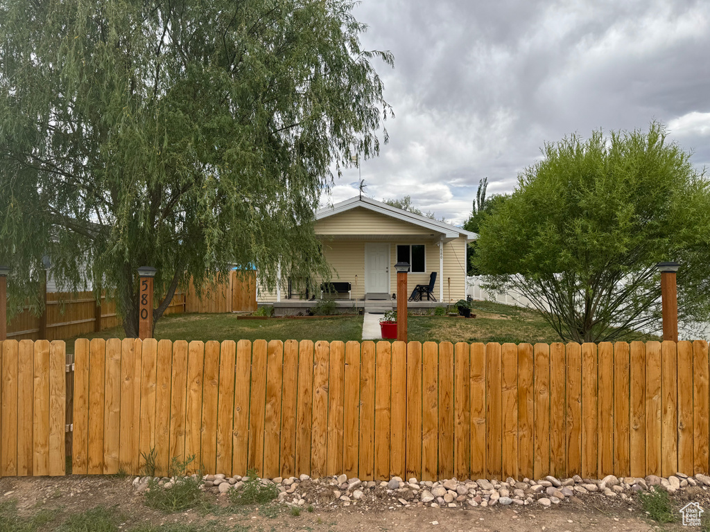Bungalow featuring covered porch, a fenced front yard, and a gate
