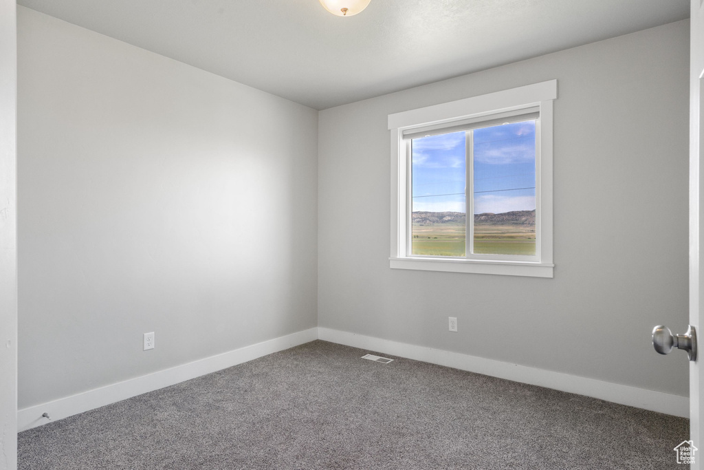 Carpeted spare room featuring baseboards