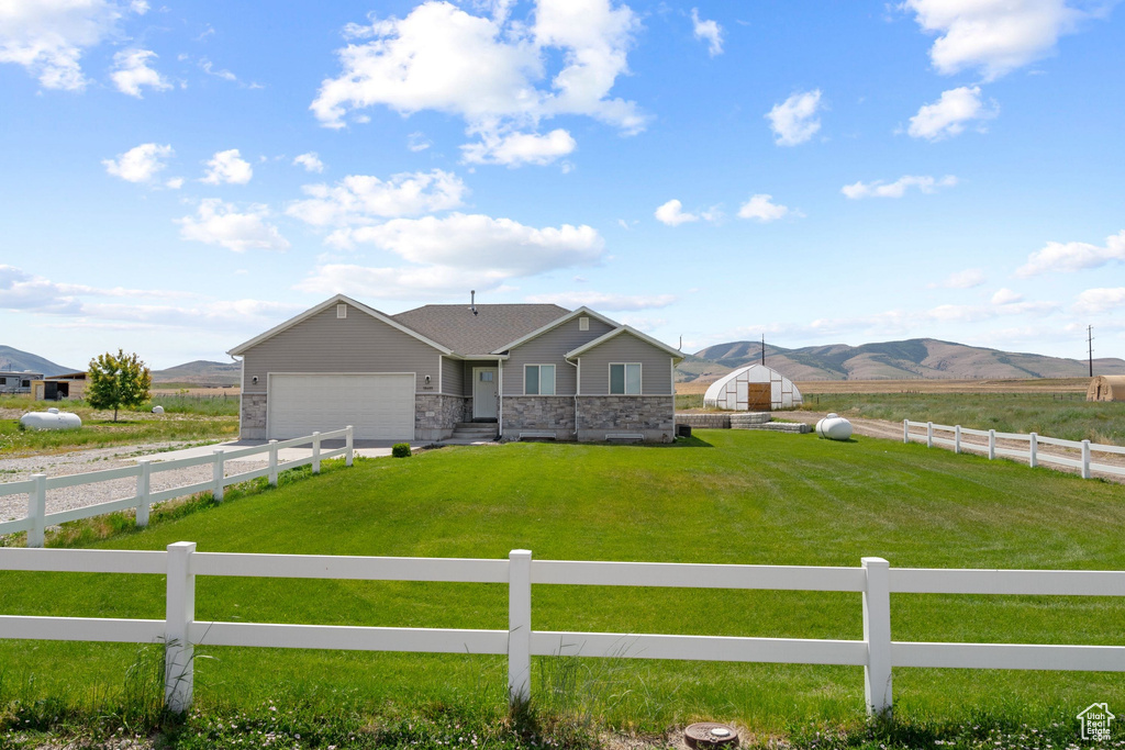 Ranch-style home with a fenced front yard, a mountain view, an attached garage, and a view of countryside