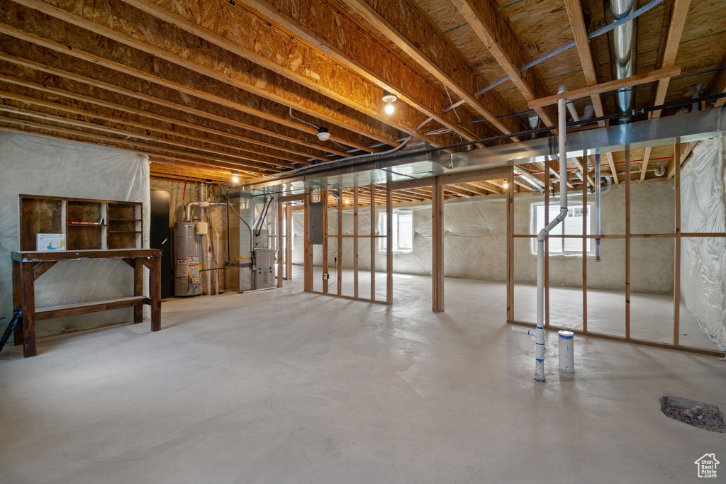 Basement with gas water heater, heating unit, and electric panel