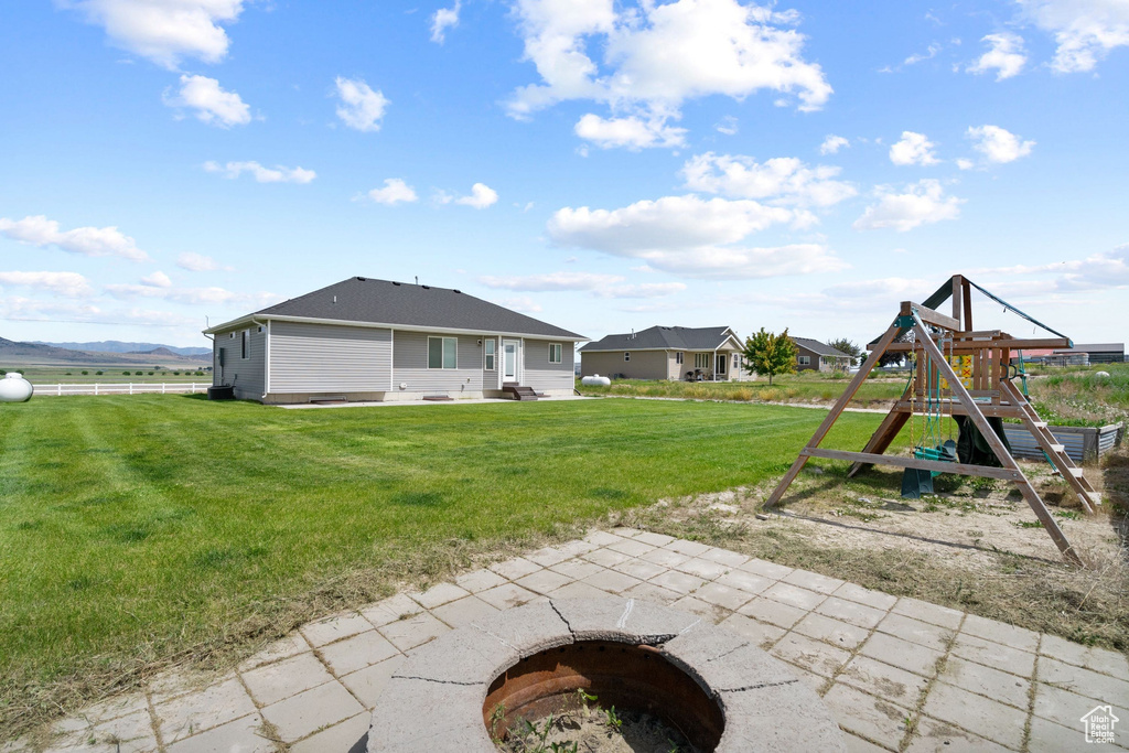 Back of house with a playground, a lawn, and a patio area