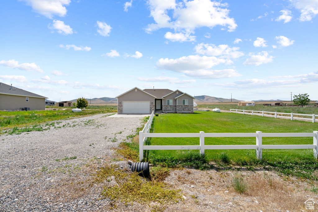 View of front of property featuring driveway, an attached garage, and a rural view