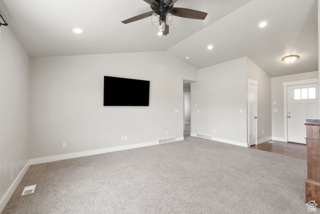 Unfurnished living room with dark carpet, ceiling fan, lofted ceiling, and recessed lighting