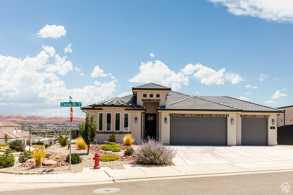 Prairie-style house with a garage, concrete driveway, stucco siding, a tile roof, and a mountain view