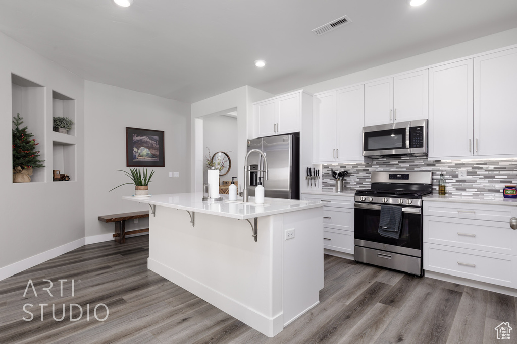 Kitchen featuring stainless steel appliances, recessed lighting, a breakfast bar area, backsplash, and dark wood-style floors