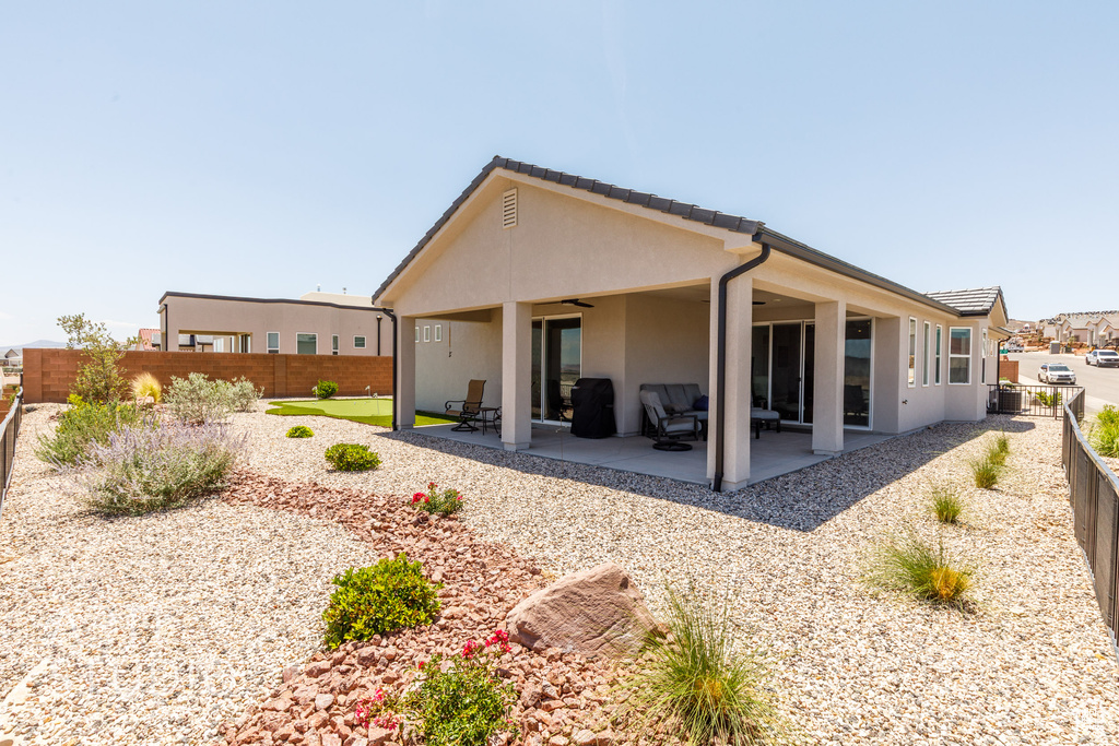 Back of house with stucco siding, ceiling fan, a fenced backyard, and a patio area