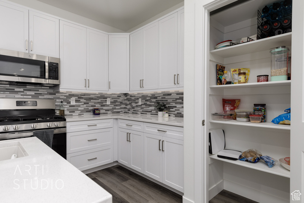 Kitchen with appliances with stainless steel finishes, dark wood finished floors, light countertops, and white cabinets