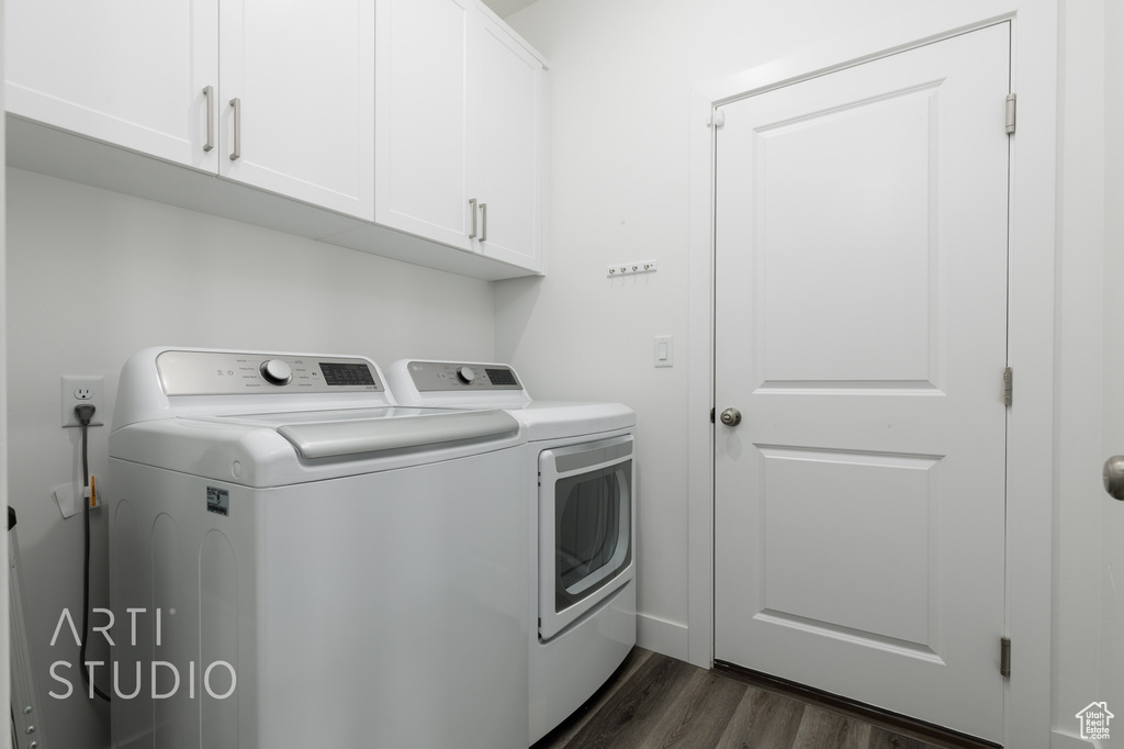 Laundry room with washing machine and clothes dryer, cabinet space, and dark wood-style flooring