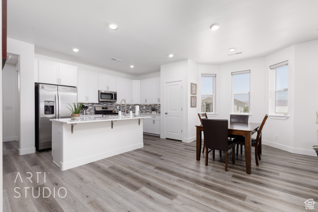 Kitchen featuring stainless steel appliances, light countertops, a breakfast bar area, white cabinets, and recessed lighting