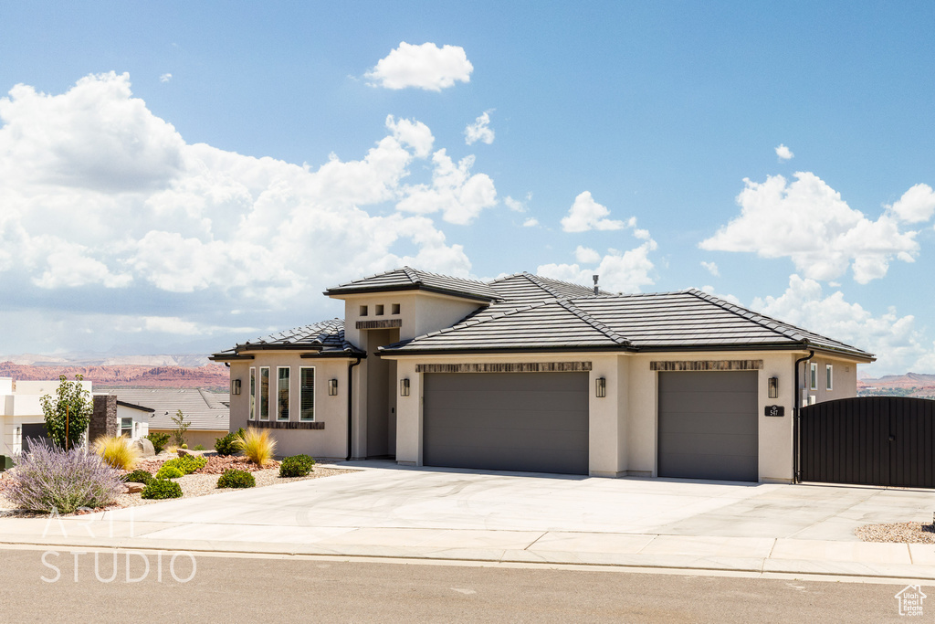 View of front of house featuring a garage, concrete driveway, stucco siding, a tiled roof, and a gate