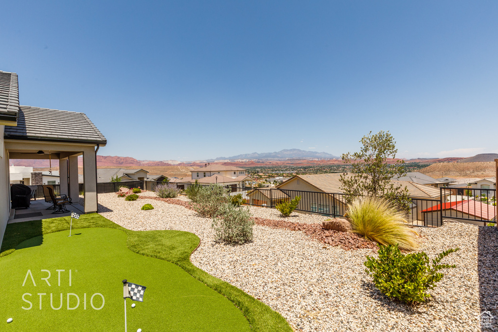 Fenced backyard with a patio area, a putting area, a mountain view, and a residential view