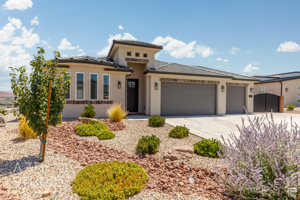 View of front facade with a garage, concrete driveway, stucco siding, a gate, and a tiled roof