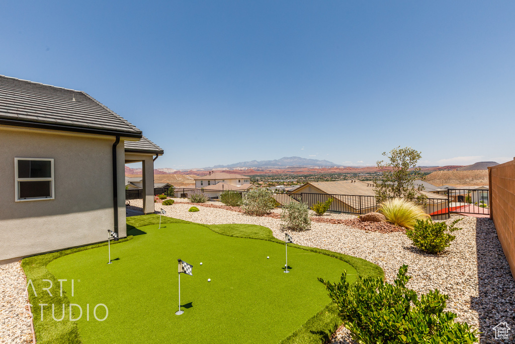 Fenced backyard featuring a putting green and a mountain view