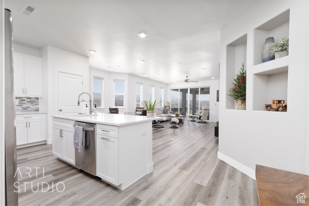 Kitchen with stainless steel appliances, light wood finished floors, white cabinetry, a kitchen island with sink, and recessed lighting