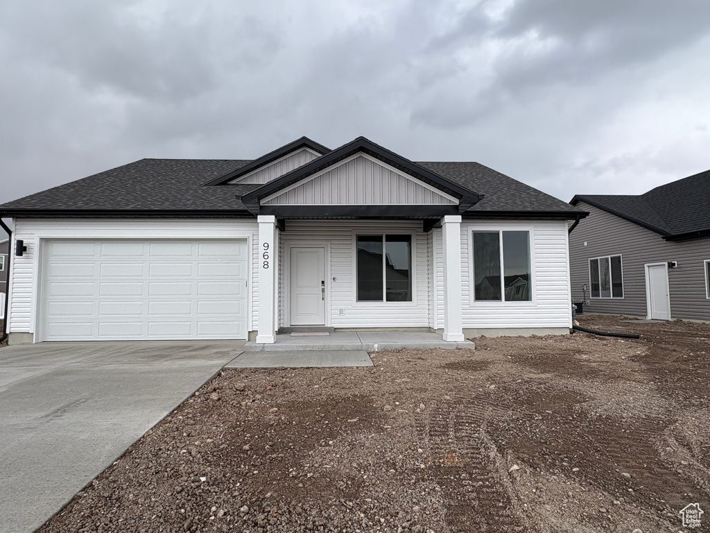 Ranch-style home featuring driveway, an attached garage, a shingled roof, and a porch