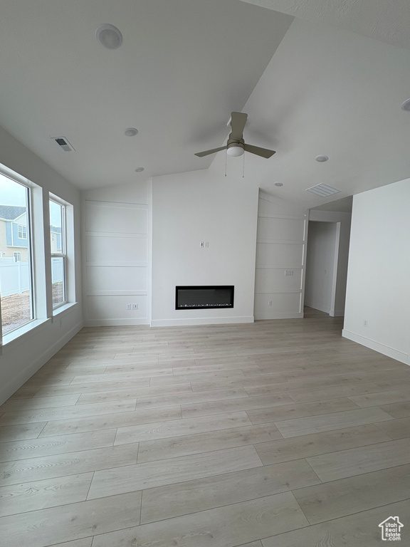Unfurnished living room with lofted ceiling, a ceiling fan, light wood-style flooring, and a fireplace