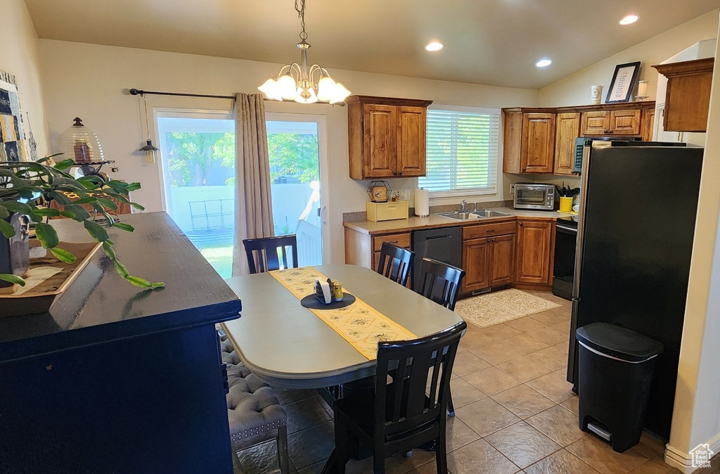Kitchen featuring brown cabinetry, a chandelier, freestanding refrigerator, a sink, and dishwashing machine